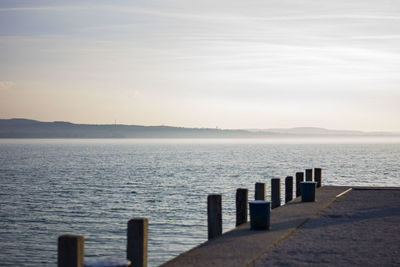 Wooden posts in sea against sky