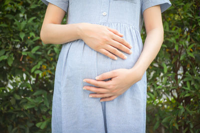 Midsection of pregnant woman standing at park