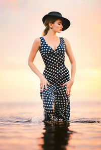 Beautiful woman standing in sea during sunset