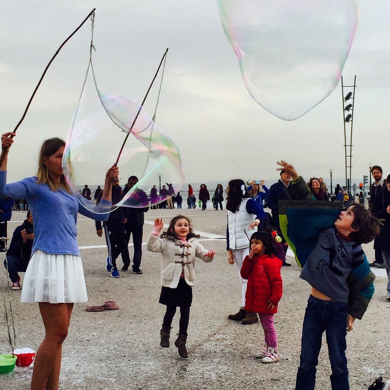 large group of people, lifestyles, leisure activity, men, person, enjoyment, fun, casual clothing, togetherness, standing, crowd, sky, vacations, sport, day, mixed age range, outdoors, holding, playing