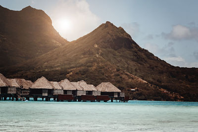 Bora bora huts in the ocean - mountains in the background - pacific ocean