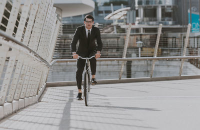 Full length of man riding bicycle on city