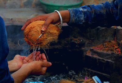 Cropped image of hand holding coconut at temple