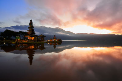 Reflection of mosque in lake against sky during sunset