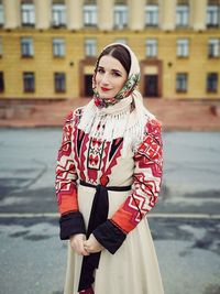 Portrait of smiling woman standing on road against building 