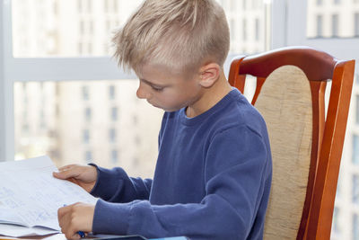 Rear view of boy sitting on table