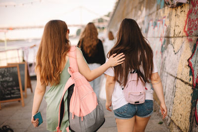 Back view of lesbian couple talking while walking in city in summer