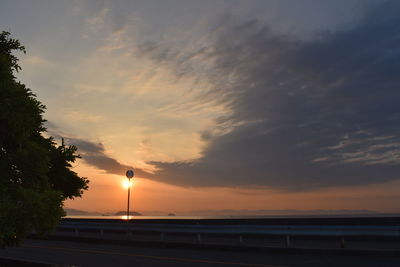 Silhouette trees by sea against sky during sunset