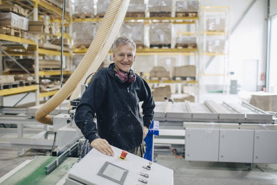 Smiling mature worker standing by machinery at industry