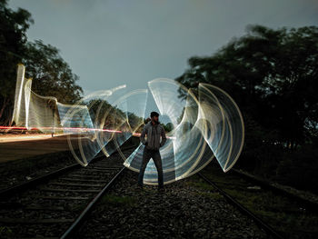 Digital composite image of man standing by railroad tracks against sky