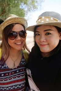 Close-up portrait of smiling friends wearing hats standing outdoors