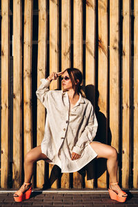 Young woman looking away while sitting on wood against wall