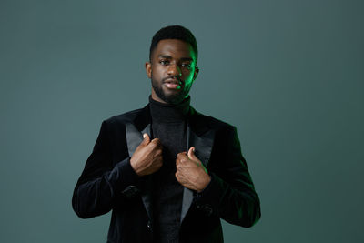 Portrait of young man standing against black background