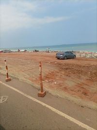 Cars on road by sea against sky