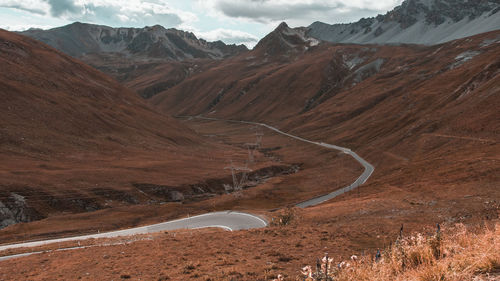 Scenic view of road by mountains against sky
