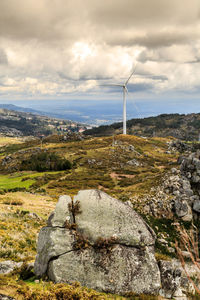 Wind turbines on landscape against sky