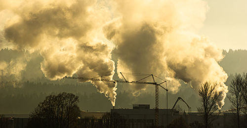 Smoke emitting from factory against sky