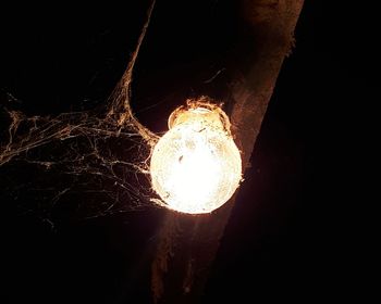 Low angle view of illuminated light bulb over black background