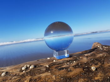 Close-up of crystal ball against clear blue sky