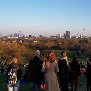 Rear view of people walking on cityscape against clear sky