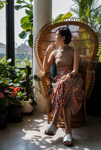 Woman looking away while standing on potted plant