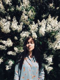 Beautiful young woman standing by flower tree