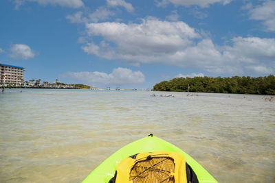 Sun shines through the clouds over a green kayak in the water of new pass in bonita springs, florida