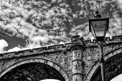 Low angle view of street light by building against sky