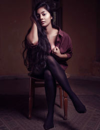 Portrait of young woman sitting on chair at home