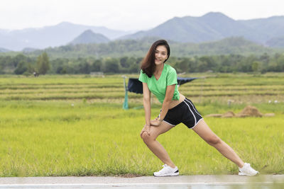 Full length portrait of a smiling young woman on field