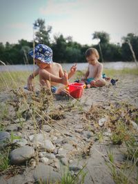 Children playing on lakeshore against sky