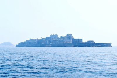 Sea by buildings against clear sky