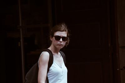 Portrait of young woman standing against wall