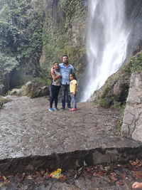 Rear view of friends on rock against waterfall