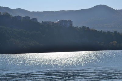 Scenic view of sea by mountains against sky