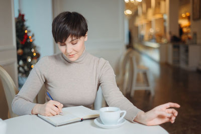 Woman writing in diary while sitting at cafe