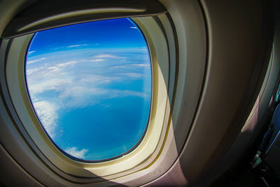 Reflection of clouds in sky seen through airplane window