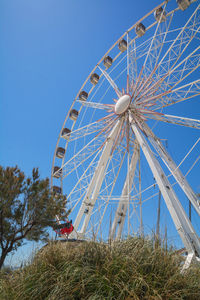 Low angle view of ferris wheel against clear blue sky