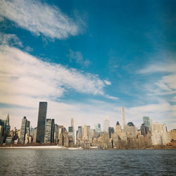 Sea by buildings in city against sky