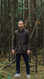 Portrait of man standing against trees in forest
