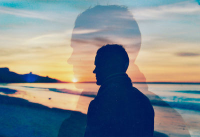 Silhouette woman standing at beach during sunset