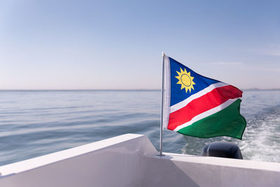 Flag on ocean against blue sky