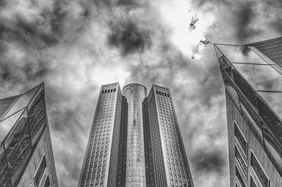 Low angle view of skyscrapers against cloudy sky