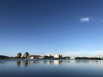 Buildings by river against blue sky