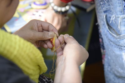 Close-up of woman sewing with thread outdoors