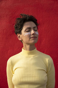 Woman with text on cheeks in front of red wall