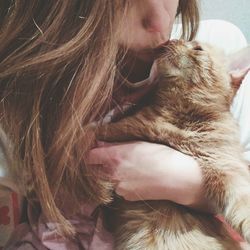 Cropped image of woman kissing cat