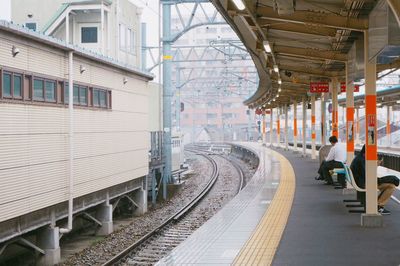 People sitting on bench waiting for train at railroad station