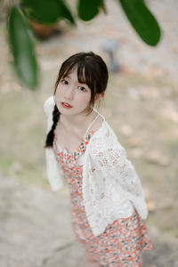 Portrait of young woman standing against plants