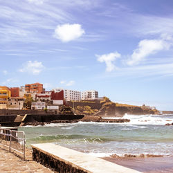 Buildings by sea against sky
